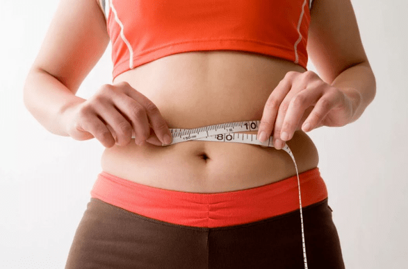 The girl measures the waist volume